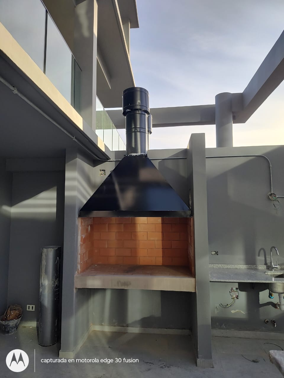 Campana negra instalada sobre parrilla con conducto exterior